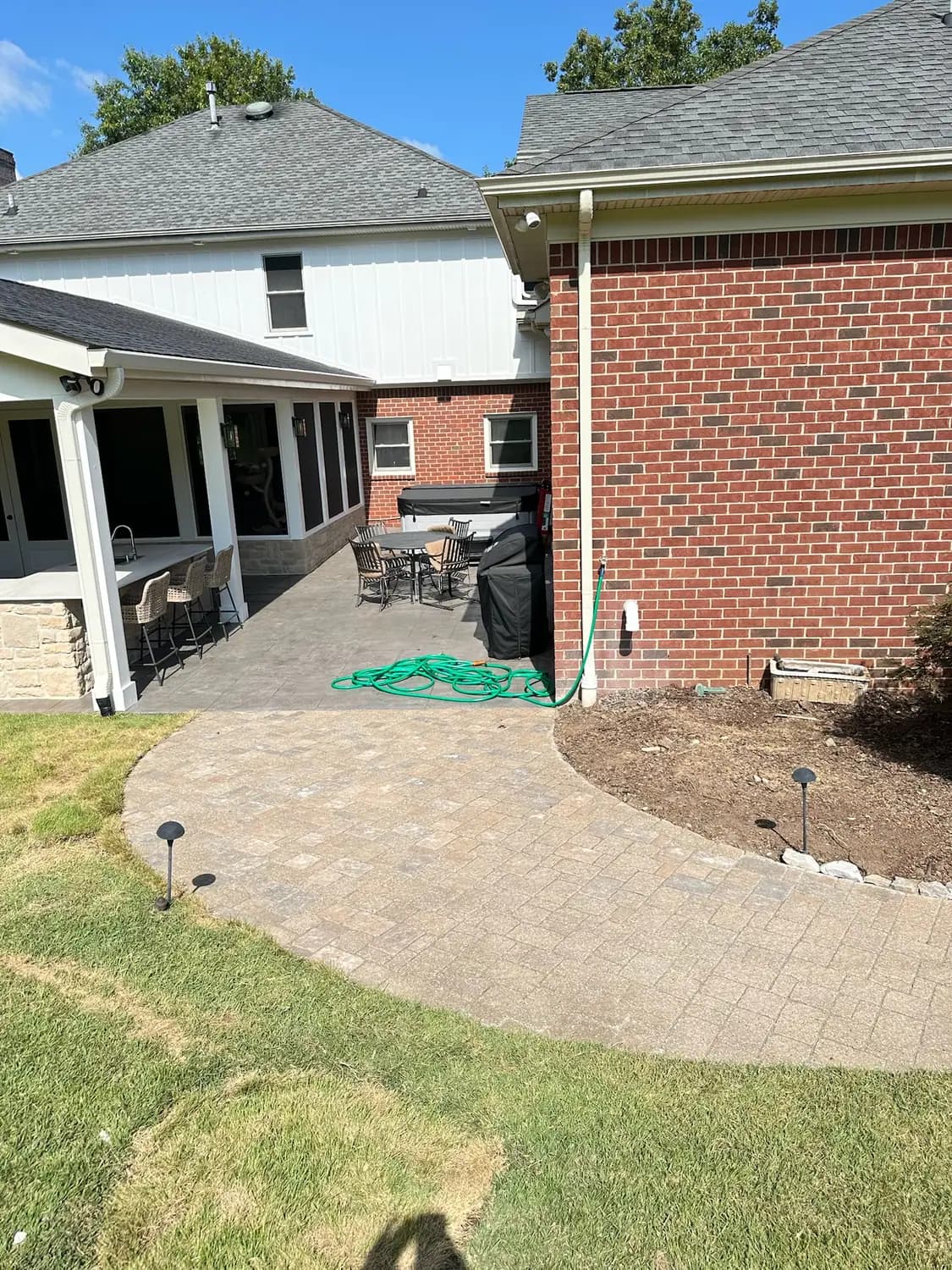 Paver patio wrapping the rear of a brick home
