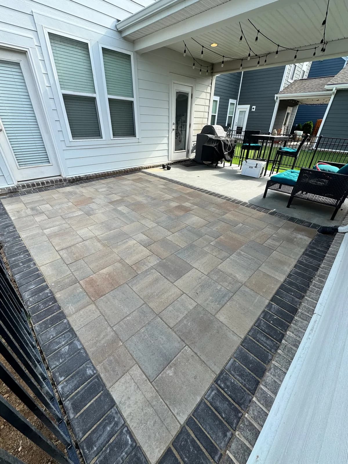 Paver patio with a charcoal soldier-course border off a covered porch
