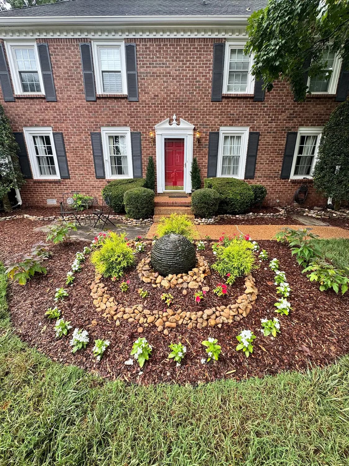 Front landscape bed with a bubbling water feature and river rock