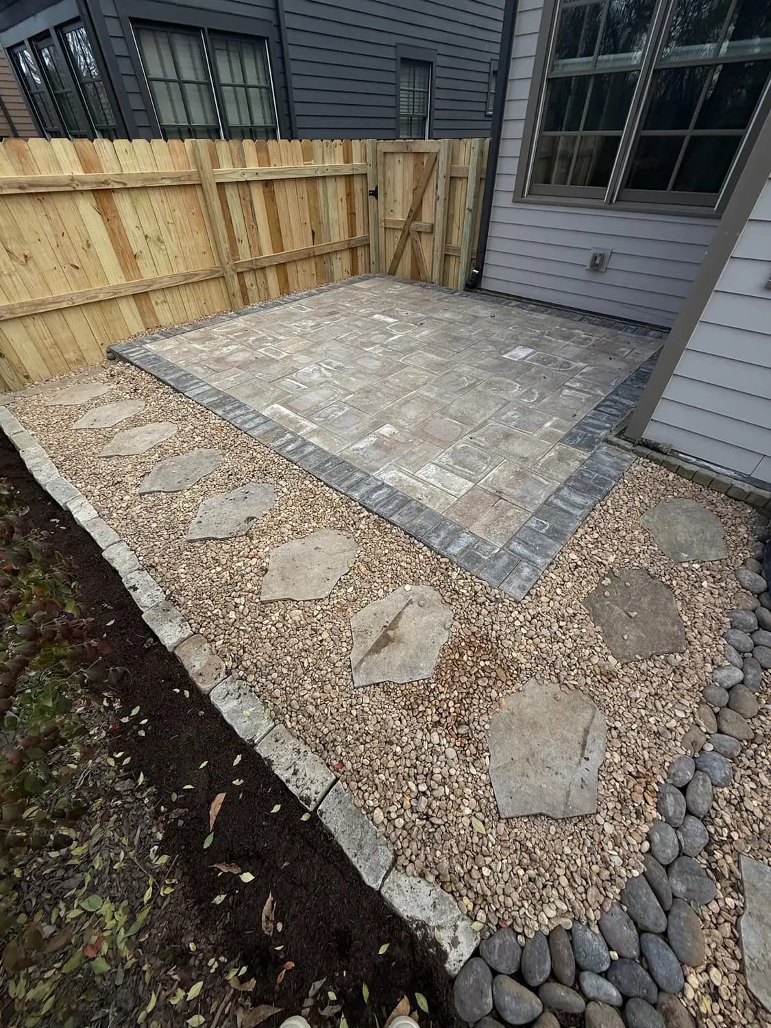 Paver patio with flagstone steppers and a river rock border