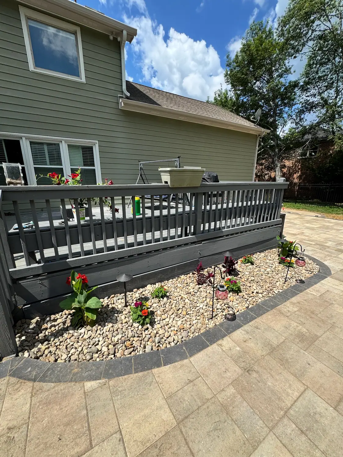 Paver patio with a river rock drainage bed along the deck