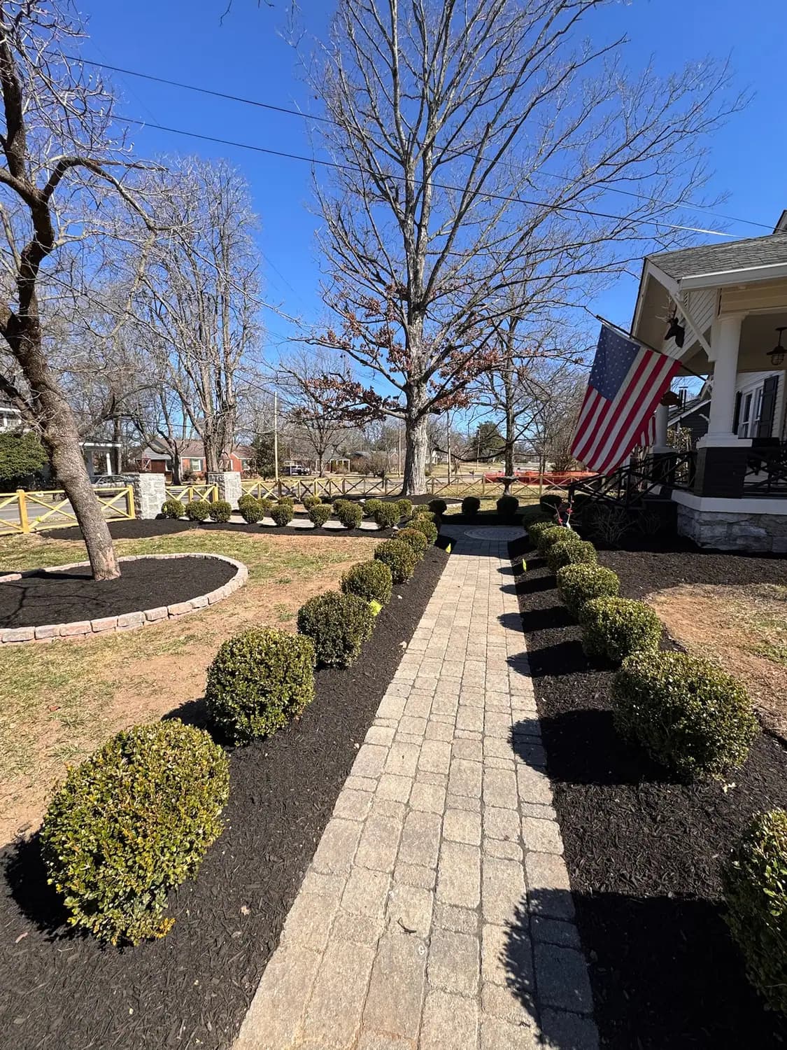 Paver walkway framed by clipped boxwoods and mulched beds
