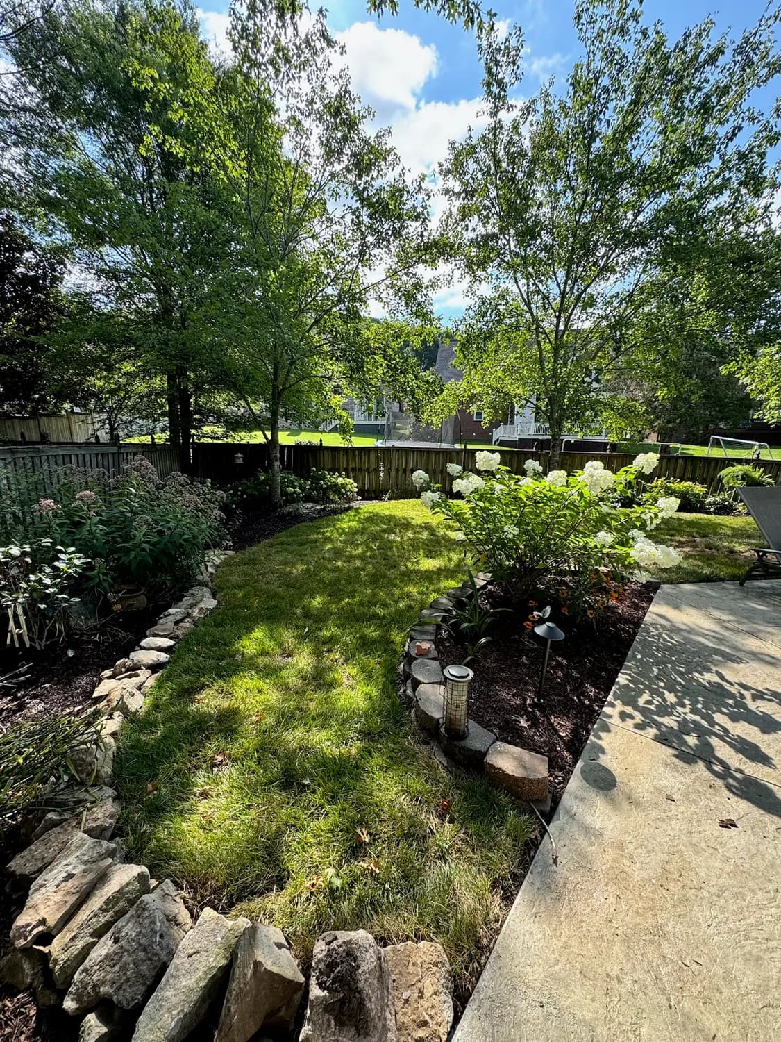 Stone-edged planting bed beside a lawn and walkway